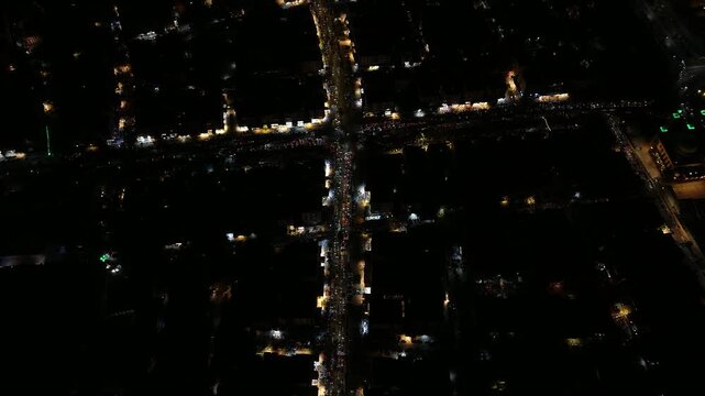 Aerial night view of an urban landscape in Syria featuring glowing city lights and illuminated streets.  Post-war Syrian cityscape and daily life at night.