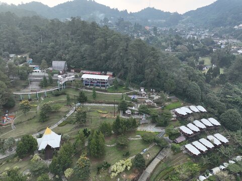 Aerial view of Ciloto park area with lush green hills, walking paths, and small buildings in Cipanas, West Java, Indonesia.