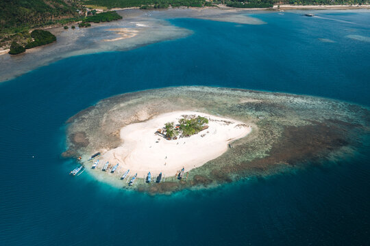 Aerial view of Gili Kedis with its white sand beach, turquoise water, and small boats anchored along the shore in Sekotong, West Nusa Tenggara, Indonesia.