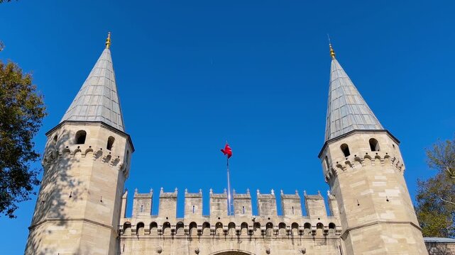 Front view: Turkish national flag with crescent and star waving in the wind above Dolmabahce Palace gate in Istanbul, historic architecture, national symbol, patriotism and sovereignty