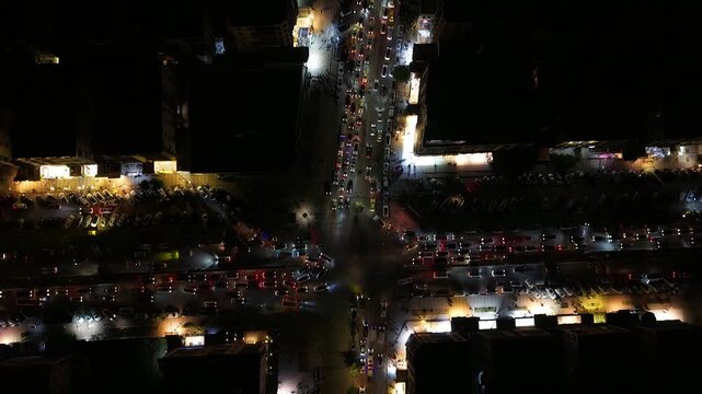 Aerial night view of an urban landscape in Syria featuring glowing city lights and illuminated streets.  Post-war Syrian cityscape and daily life at night.