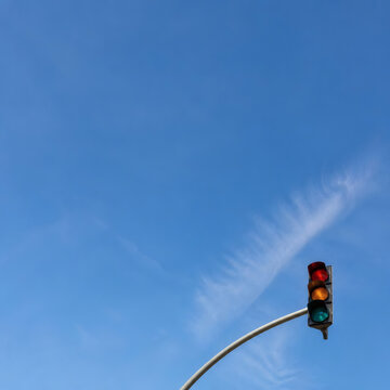 Traffic Signal Light Hanging Against a Bright Clear Blue Sky with Wispy Clouds Concept of Urban Direction and Safety