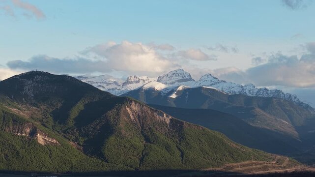 Winter aerial view toward Sierra de Partacua at the entrance to Tena Valley in Huesca, Spain, with snow-covered Pyrenees peaks, forested slopes and mountain ridges under clear morning light
