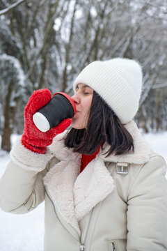 Woman Enjoying Hot Drink in Snowy Forest.