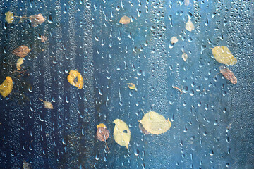 Naklejka premium Drops on the window, autumn leaves, abstract autumn weather background
