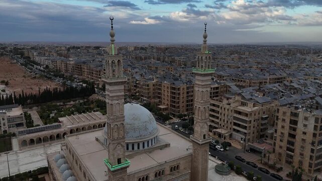 Aerial drone view of an Islamic mosque featuring a prominent dome and tall minarets. Concept of world religions, faith, and Islamic culture in post-war Syria.