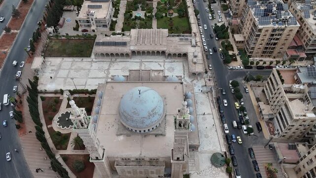 Aerial drone view of an Islamic mosque featuring a prominent dome and tall minarets. Concept of world religions, faith, and Islamic culture in post-war Syria.