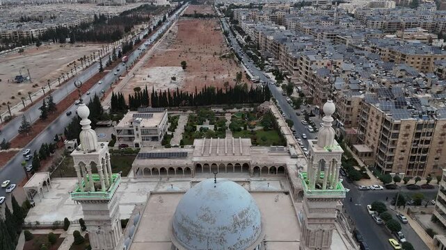 Aerial drone view of an Islamic mosque featuring a prominent dome and tall minarets. Concept of world religions, faith, and Islamic culture in post-war Syria.