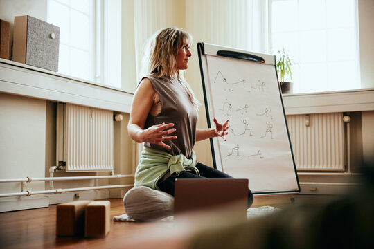 Yoga teacher demonstrating breathing teqchniques. On a board next to her, she has listed the techniques.