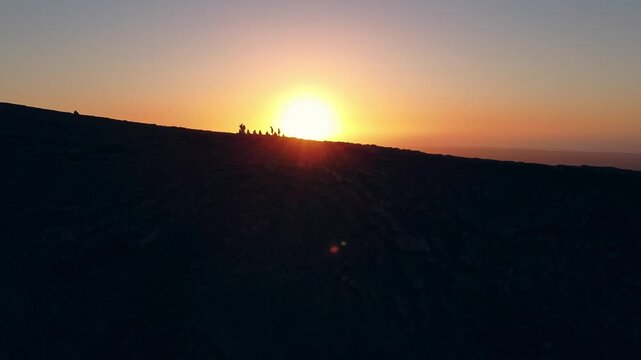 Small group of people admiring the sunset from the top of a volcano in fuerteventura