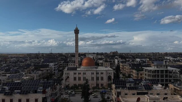 Aerial drone view of an Islamic mosque featuring a prominent dome and tall minarets. Concept of world religions, faith, and Islamic culture in post-war Syria.