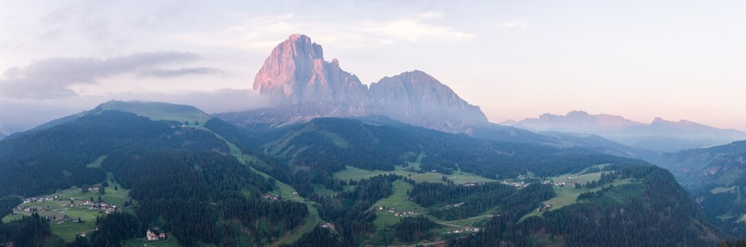 Panoramic landscape view of Sassolungo mountain group in the Dolomites with morning alpenglow at sunrise, Alpe di Siusi, South Tyrol, Italy.