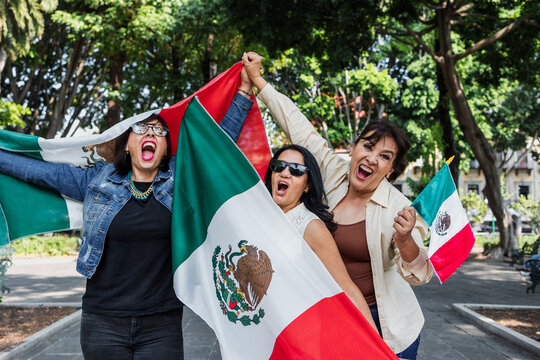 Mexican senior women with flags to celebrate mexican independence day and cheering Viva Mexico, mature people having fun