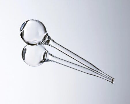Clear glass double-headed ladle against light gray background.