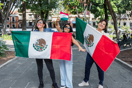 Mexican senior women with flags to celebrate mexican independence day and cheering Viva Mexico, mature people having fun
