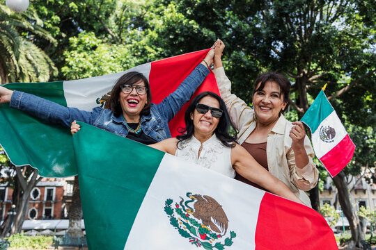 Mexican senior women with flags to celebrate mexican independence day and cheering Viva Mexico, mature people having fun
