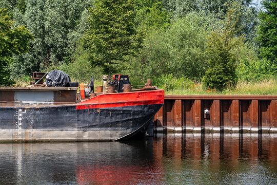 Close up view of red and black cargo barge bow moored at steel sheet pile wall on canal in Brandenburg Germany