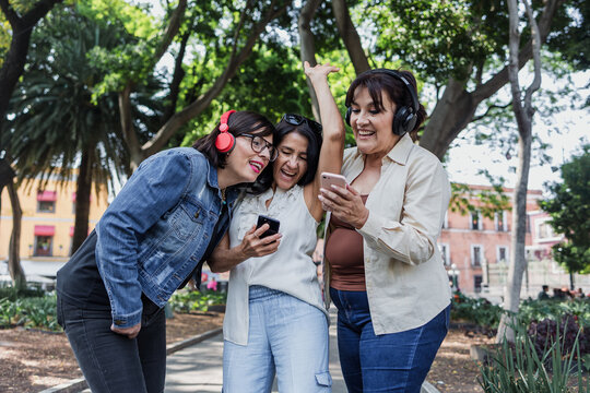 latin senior friends listening music in public park in Mexico Latin America, mexican middle age females having fun outdoors