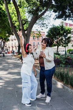 latin senior friends listening music in public park in Mexico Latin America, mexican middle age females having fun outdoors