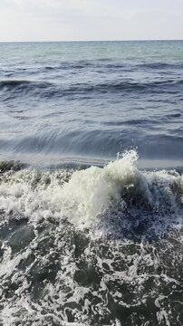 Close up of ocean wave breaking with white foam on shore
