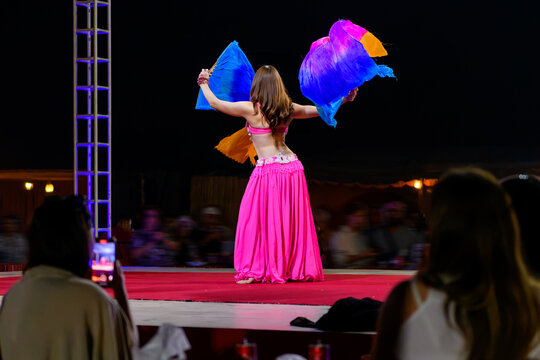 A belly dance performance on stage at night in a desert camp specializing in tourist performances in the Sharjah Dubai desert, United Arab Emirates.