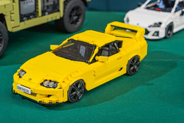 Fototapeta premium Summary Collection of Lego model cars, primarily sports and race cars with some trucks, arranged on a vibrant green surface Prominent yellow LEGO sports car at - Kyiv, Ukraine - June 7, 2025