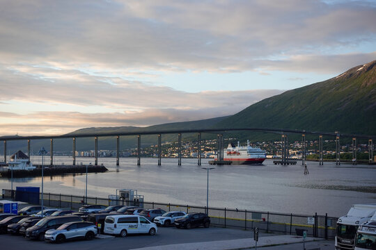 Tromso, Norway, June 19th 2026: A Hurtigruten ship lies alongside the harbor in Troms&oslash;, with the striking Arctic Cathedral rising across the water, capturing the unique blend of maritime heritage	