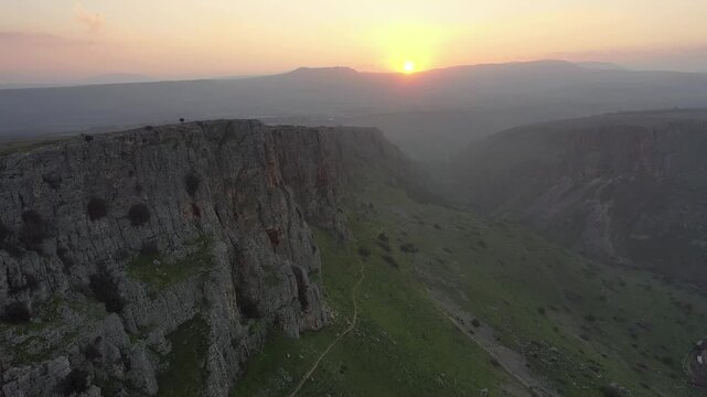 Aerial view of the rugged cliffs of Mount Arbel and the surrounding landscape during golden hour in Kinneret, North District, Israel.