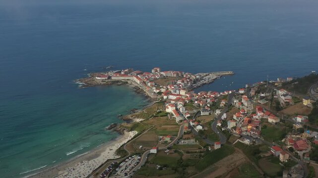 Aerial view of the coastal town of Caion with its harbor, sandy beach, and residential buildings along the Atlantic coastline in Caion, A Coruna, Spain.