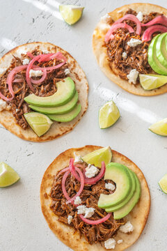 Open faced pulled beef tacos with avocado pickled onions queso fresco lime