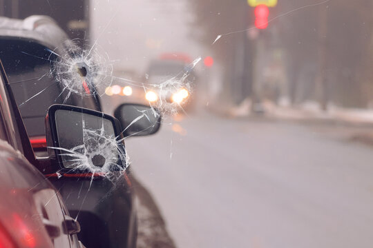 A broken car windshield with bullet or stone holes.