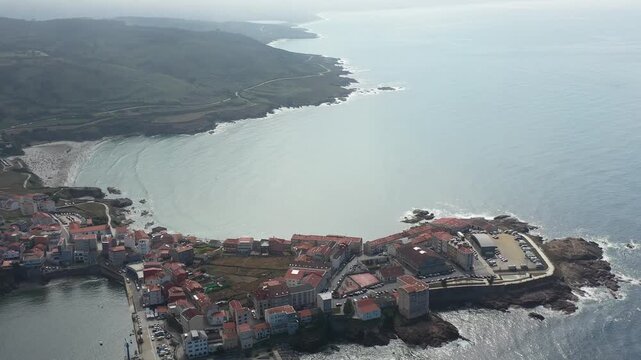 Aerial view of the coastal town of Caion with its harbor, sandy beach, and rocky shoreline along the Atlantic Ocean in Caion, A Coruna, Spain.
