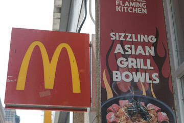 Fototapeta premium two projecting signs on the exterior of McDonald's Canada fast food restaurant (470 Yonge St) and Flaming Kitchen (472 Yonge St), Toronto