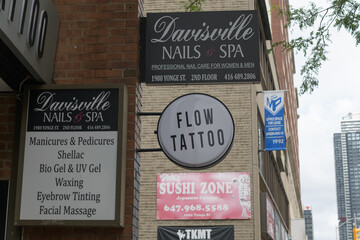 Fototapeta premium signage around Flow Tattoo located at 1980 Yonge St, Toronto (Sushi Zone, Davisville Nails & Spa)