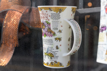 Fototapeta premium cup inside grungy display window at Hockridge China 638 Yonge St, Toronto (Dunoon’s “World of Bees” Glencoe mug, designed by Caroline Dadd and handcrafted in fine bone china in Staffordshire, England)