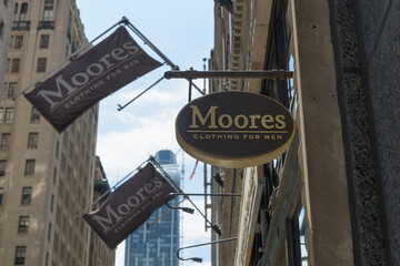 Fototapeta premium signs and flags outside Moores Clothing for Men located at 100 Yonge St, Toronto