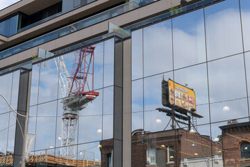Fototapeta premium rooftop billboard with McDonald's Canada advertising, and crane at the One Roxborough West development, all reflected off the mirrored windows at 1027 Yonge St, Toronto