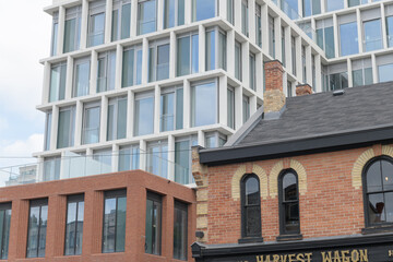 Fototapeta premium wide, contextual view of Harvest Wagon (1103 Yonge St, a gourmet grocery store, with contrasting 19th century commercial architecture and The James, a new condo in Toronto
