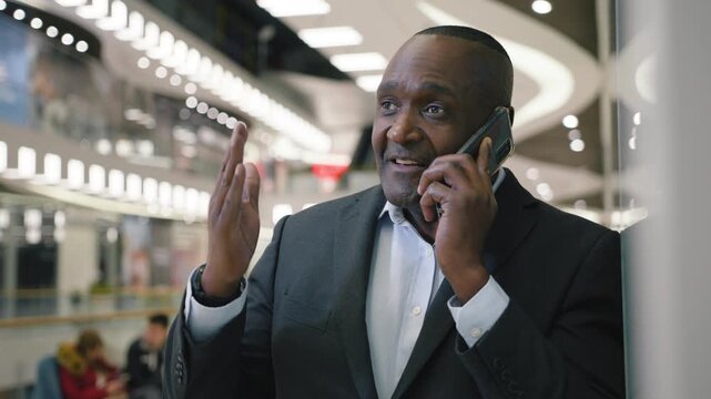 Happy African American middle-aged business man talking mobile phone smiling in corporate company positive mature businessman smile talk smartphone call enjoying pleasant conversation in shopping mall