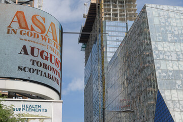 Fototapeta premium digital billboard with concert promotion for Asake + Uncle Waffles at Scotiabank Arena on roof of Healthy Planet (322 Yonge St) - at right, Sheldon & Tracy Levy Student Learning Centre, TMU, Toronto