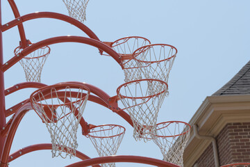 Fototapeta premium view of Alexandre Arrechea's Orange Functional, 2022, composed of steel and basketball nets, #1, in the plaza of Old Firehall 30, at Biidaasige Park, Port Lands, Toronto
