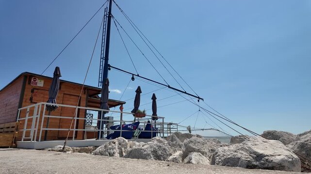 Senigallia, Italy - June 25, 2026 - Wooden beachside structure with fishing nets and clear blue sky