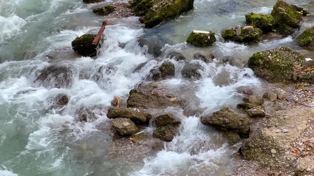 Fast flowing Moraca river with rocky rapids in Podgorica, Montenegro. Clear water creating white foam, rushing over moss covered stones and canyon thresholds