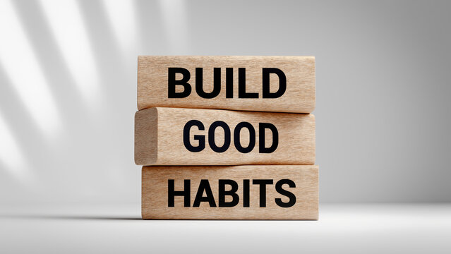 Wooden blocks with text build good habits stacked for personal development and productivity improvement on a soft light grey background with shadow effects