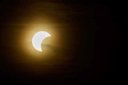 Solar eclipse over the landscape, showing dark lunar silhouette gliding across the solar disk
