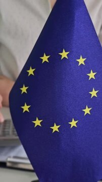 Displaying the European Union flag in a workspace setting with hands visible
