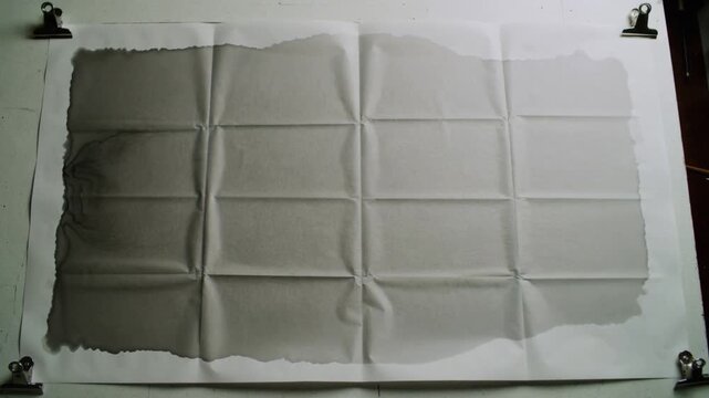 Frames advancing large sheet 4x4 crease grid slowly deepening gray wash on bench, binder clips