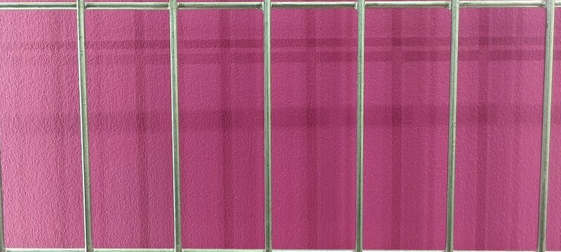 Minimalist composition of silver metal bars forming a rectangular grid over a textured pink background, highlighting contrast between smooth metallic lines and rough surface.