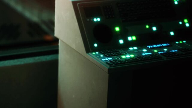 Light streams from equipment in a dark room. Shadows create a mysterious atmosphere. This scene shows a workspace during late night hours with focused details on tech devices.