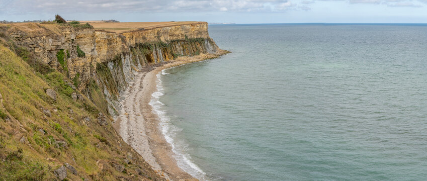 Arromanches-les-Bains, France - 08 10 2026:  Coastal path. Panoramic view of the cliffs and the sea and cloudy sky from top of the path